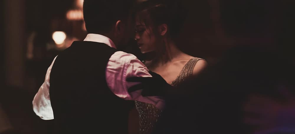 A couple dancing close in a dim, warmly lit room